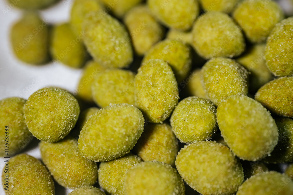 A close-up view of bright yellow-green wasabi-flavored nuts coated in a fine powder, creating a spicy and crunchy snack. Blurred background for emphasis. A close-up view of bright yellow-green wasabi-flavored nuts coated in a fine powder, creating a spicy and crunchy snack. Blurred background for emphasis.