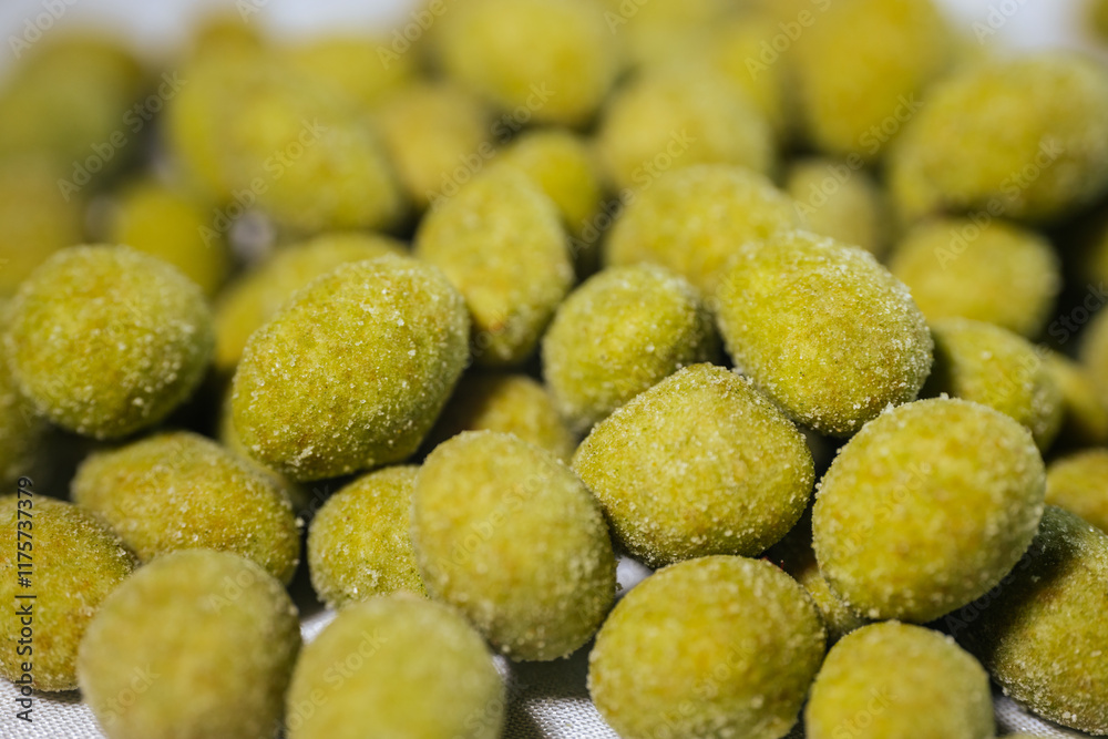 A close-up view of bright yellow-green wasabi-flavored nuts coated in a fine powder, creating a spicy and crunchy snack. Blurred background for emphasis. A close-up view of bright yellow-green wasabi-flavored nuts coated in a fine powder, creating a spicy and crunchy snack. Blurred background for emphasis.