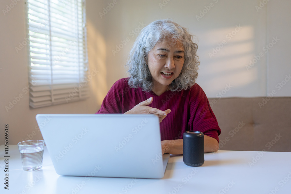 Senior woman talking to smart speaker while using laptop Senior woman talking to smart speaker while using laptop