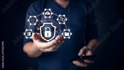 A person holding a glowing shield icon symbolizing cyber security, surrounded by connected digital icons representing data protection, secure networks, and technology safeguards in a dark setting.