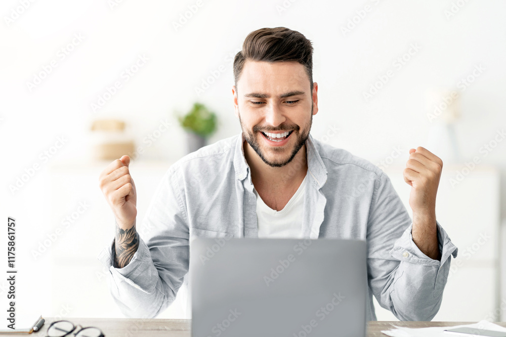 Joyful young man shaking fists looking at laptop computer screen celebrating business success, sitting at workplace at home. Great news and victory celebration, successful career concept Joyful young man shaking fists looking at laptop computer screen celebrating business success, sitting at workplace at home. Great news and victory celebration, successful career concept