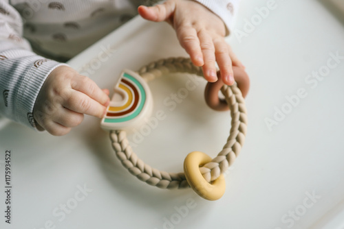 Foto Baby holding a silicone rainbow teether with braided handle and pastel-colored details