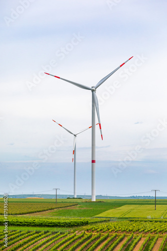 Two Wind Power Generators (Windmills) surrounded by green Crop Farming Fields on a sunny Summer Day; Copy Space