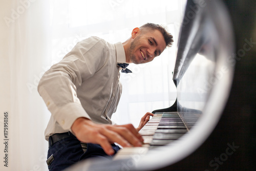 Canvas Print young guy in white shirt plays on old black piano, musician pianist performs mel