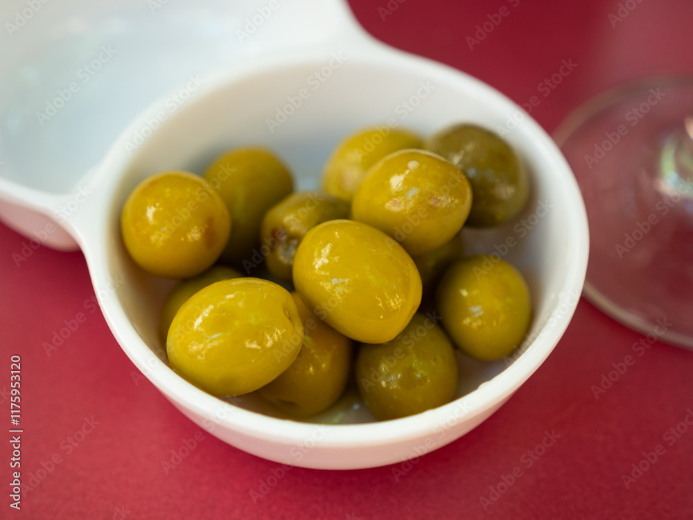 Closeup of plate of pickled green olives with a stone, spanish appetizer Closeup of plate of pickled green olives with a stone, spanish appetizer