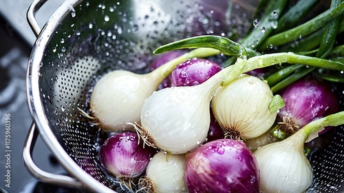 Ripe white and purple onions being washed in a metal colander with water droplets glistening photo