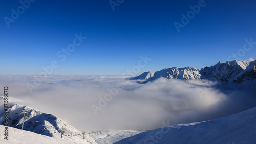 Panorama of the winter peaks of the Tatras from Kasprowy Wierch. A sunny, winter December day. The mountain peaks are covered in thick clouds.