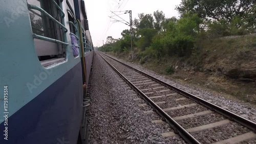 POV or first hand view of a train in india. Camera out of the train rolling next to indian train on double track. Traditional blue carriages, speeding on the tracks.