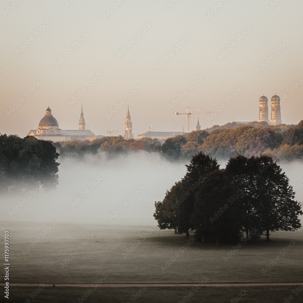 Fototapeta premium A Misty Morning View Of Munich Old Town From The English Garden With Fog Draping The Landscape And Hazy Silhouettes Of Historic Architecture