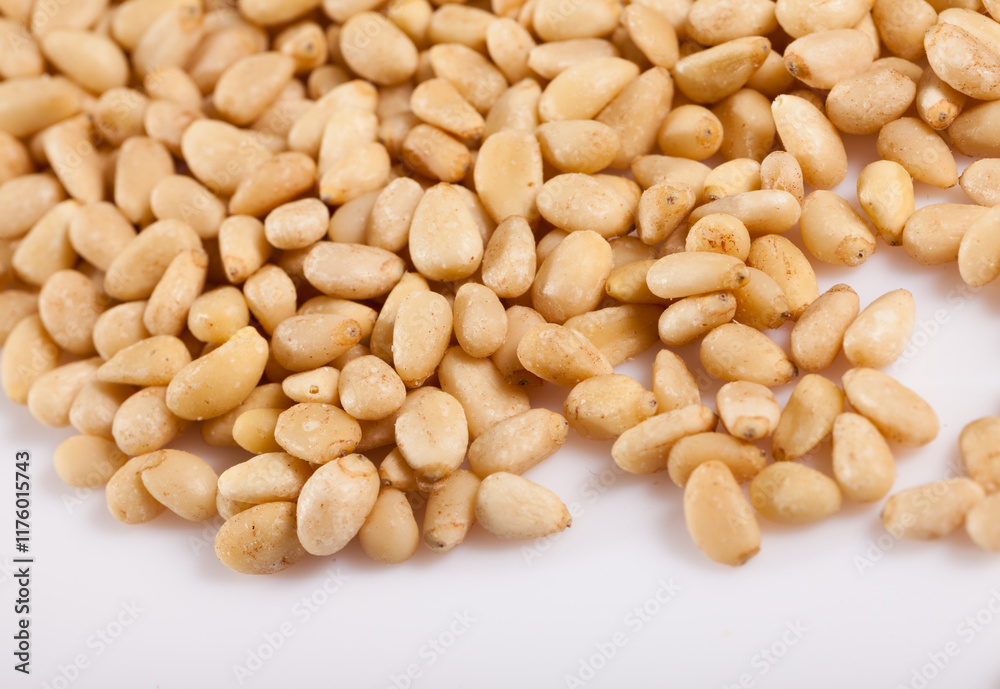 Pile of delicious pine nuts on a white surface Pile of delicious pine nuts on a white surface