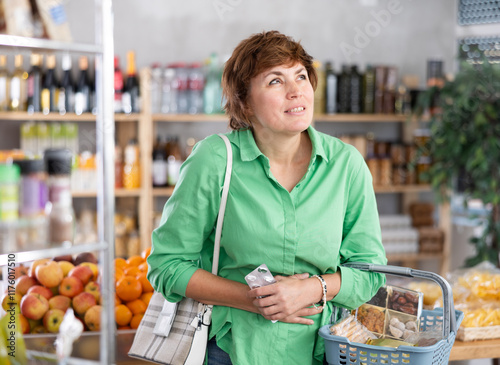 Woman feels cramps and discomfort in her abdomen while shopping at the supermarket.