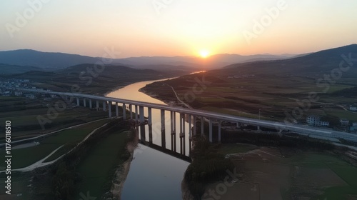 Wallpaper Mural As the sun sets, a monumental urban bridge stretches across a wide river, connecting landscapes and creating a breathtaking silhouette. Torontodigital.ca