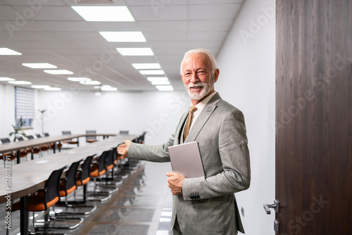 Portrait of smiling senior businessman standing in conference or meeting room.