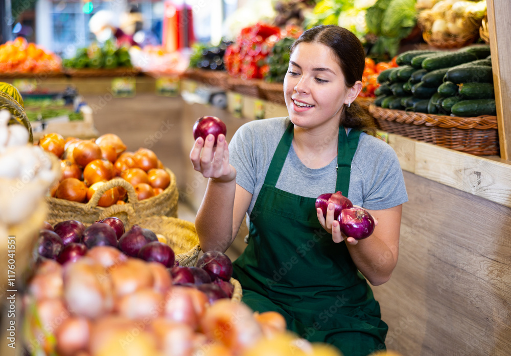 Saleswoman near fruit and vegetables stalls offering to buy red onion Saleswoman near fruit and vegetables stalls offering to buy red onion