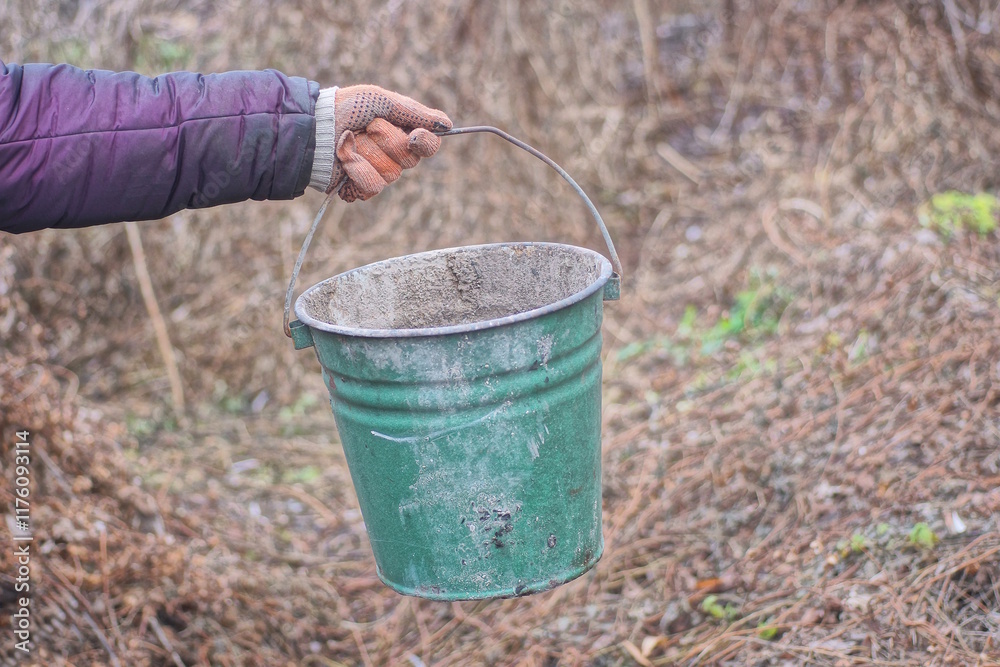 hand holding one old green dirty enamel metal bucket on autumn street hand holding one old green dirty enamel metal bucket on autumn street