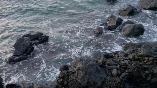 Zenithal view of a sea with large windstorm waves impacting against the cliff and rocks. Concept of erosion and danger of the sea.