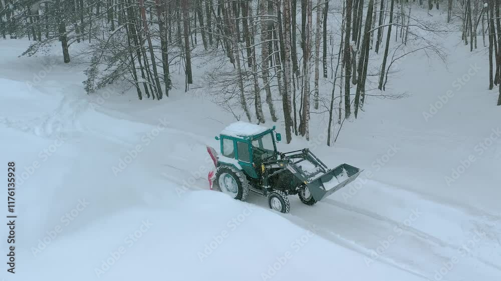 Aerial drone view of a farmer on a tractor clearing the road of snow during heavy snowfall. Snow removal work. High quality 4k footage Aerial drone view of a farmer on a tractor clearing the road of snow during heavy snowfall. Snow removal work. High quality 4k footage