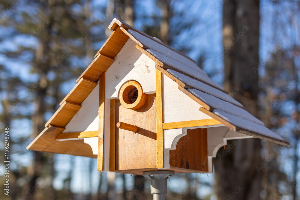 Naklejka premium Wooden Birdhouse in Winter Setting with Snow and Forest Background
