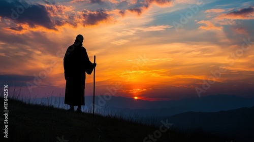 Silhouette of Jesus Christ standing with a wooden cane, illuminated by the radiant hues of a vibrant and peaceful sunset photo