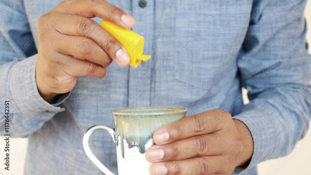 Person adding sweetener to a cup