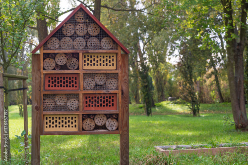 A handcrafted insect hotel in a lush green park, surrounded by trees, offers a glimpse into sustainable wildlife habitats. Perfect for projects on biodiversity, gardening, or eco-tourism. photo