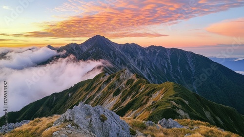 Mt. Shirouma at dawn, its silhouette etched against the pink and orange hues of sunrise, with scattered clouds framing the Ushiro-Tateyama range. photo