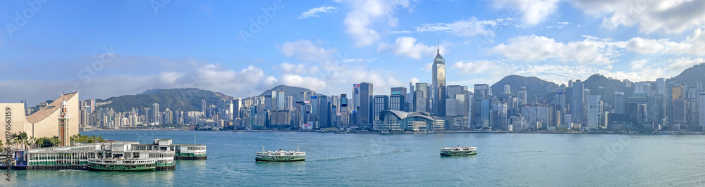 Fototapeta premium Panorama view of Hong Kong Victoria Harbour with cityscape, star ferry ships and mountains