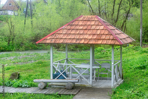 Obraz na płótnie Charming riverside gazebo surrounded by lush greenery in a tranquil setting w salonie