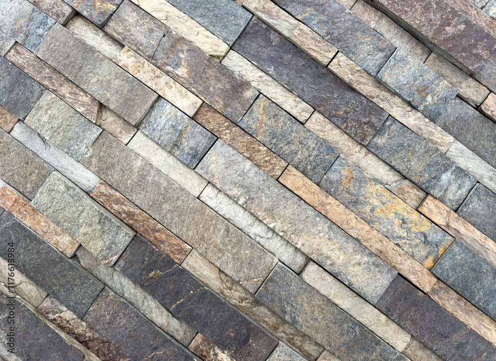 A stone wall with a pattern of brown and gray bricks A stone wall with a pattern of brown and gray bricks