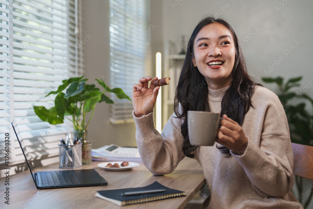 Happy young asian woman enjoying a relaxing break from work, savoring a delicious chocolate bar and sipping warm coffee at her cozy home office desk, surrounded by plants and natural light Happy young asian woman enjoying a relaxing break from work, savoring a delicious chocolate bar and sipping warm coffee at her cozy home office desk, surrounded by plants and natural light