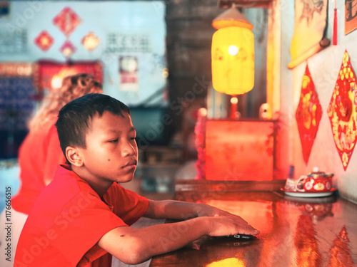 The boy in the red shirt is sitting sleepily. photo