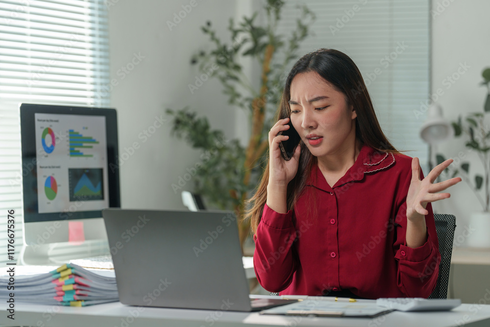 Young professional arguing on phone with client or colleague while looking at laptop and having difficulty with her online business, finance and accounting tasks Young professional arguing on phone with client or colleague while looking at laptop and having difficulty with her online business, finance and accounting tasks