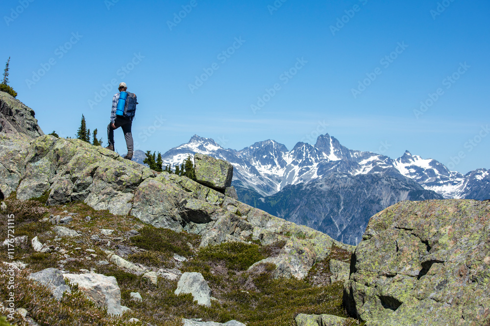 Backpacker Exploring Rugged Mountain Terrain with Snow-Capped Peaks