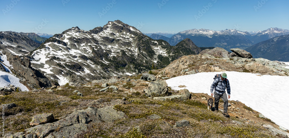 Man with dog explores rugged mountain Terrain with Snow-Capped Peaks Man with dog explores rugged mountain Terrain with Snow-Capped Peaks