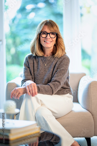 Blond haired woman relaxing in an armchair in her modern home Free Download Blond haired woman relaxing in an armchair in her modern home - GFXLoad