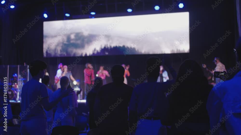 Headshot of Silhouetted Audience with Raised Hands at Worship Concert in Dark Church Auditorium at Night, african worship