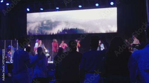 Headshot of Silhouetted Audience with Raised Hands at Worship Concert in Dark Church Auditorium at Night, african worship
