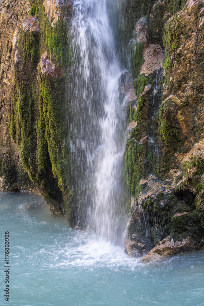 Fototapeta premium Transparent water falls in several cascades from height of 60 meters, raising cloud of tiny water particles into air. Fragment of falling streams of multi-level main waterfall Chegem with stone ledges