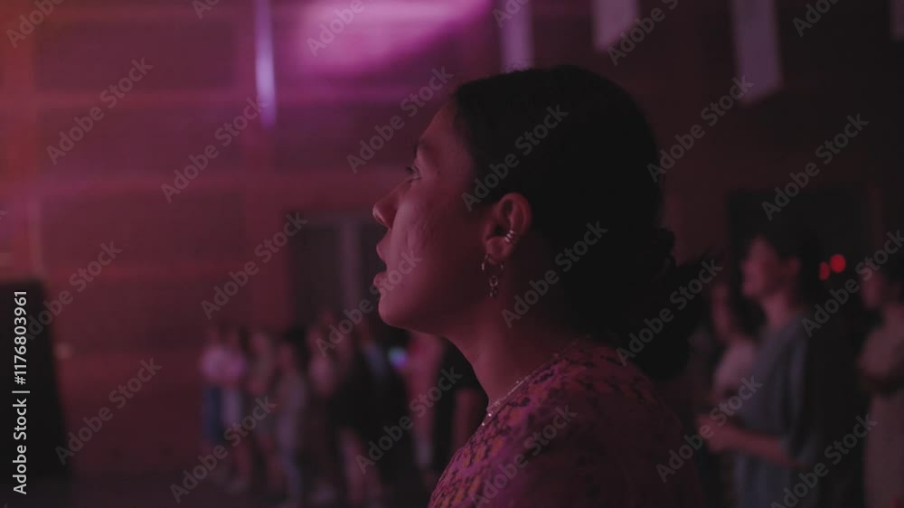 Beautiful latin female singing at concert, staying with a crowd of people during musical festival, worship night at church, worshipping God Jesus, enjoying atmosphere with young people