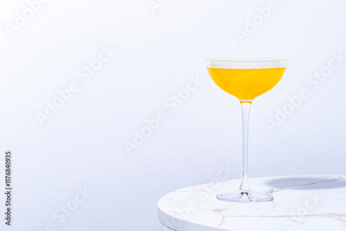 Flying Dutchman, yellow alcoholic cocktail drink with gin, liqueur and lemon juice. Marble table iand white wall photo