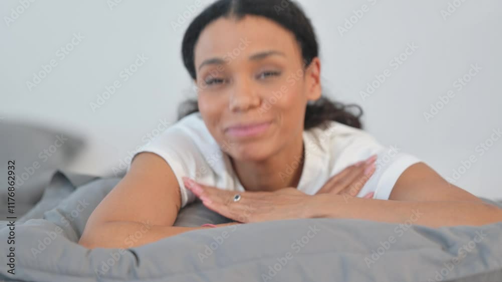 Thumbs Up by African Woman Looking at Camera while Lying on Stomach in Bed Thumbs Up by African Woman Looking at Camera while Lying on Stomach in Bed