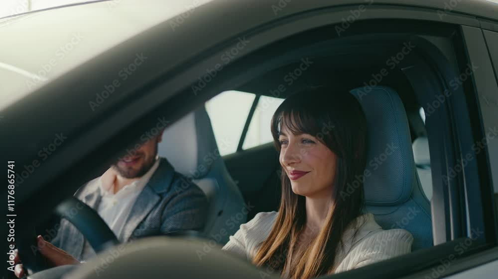 Happy Caucasian woman sitting in car and gently touching steering wheel. Inspective every detail of new vehicle. Shopping in dealership with boyfriend. Looking at camera while smiling. Happy Caucasian woman sitting in car and gently touching steering wheel. Inspective every detail of new vehicle. Shopping in dealership with boyfriend. Looking at camera while smiling.