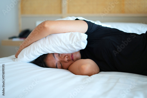 Sick young asian woman feeling sad, tired, stressed and worried suffering depression in mental health, sitting and lying on bed, covering her ears and cannot sleep well from insomnia, mental problem.