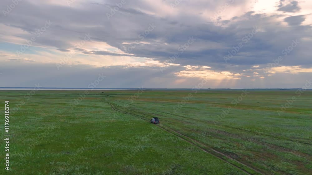 the car drives across the steppe to Lake Ebeyty at sunset the car drives across the steppe to Lake Ebeyty at sunset