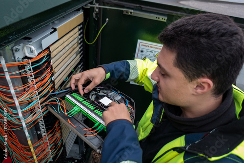 Técnico de fibra ótica a realizar reparo em armário para restaurar o acesso à rede de clientes afetados pela avaria photo