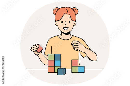 Happy little girl playing with wooden child cubes standing at table and smiling looking at screen. Child plays educational game that helps improve intellectual abilities and fine motor skills.