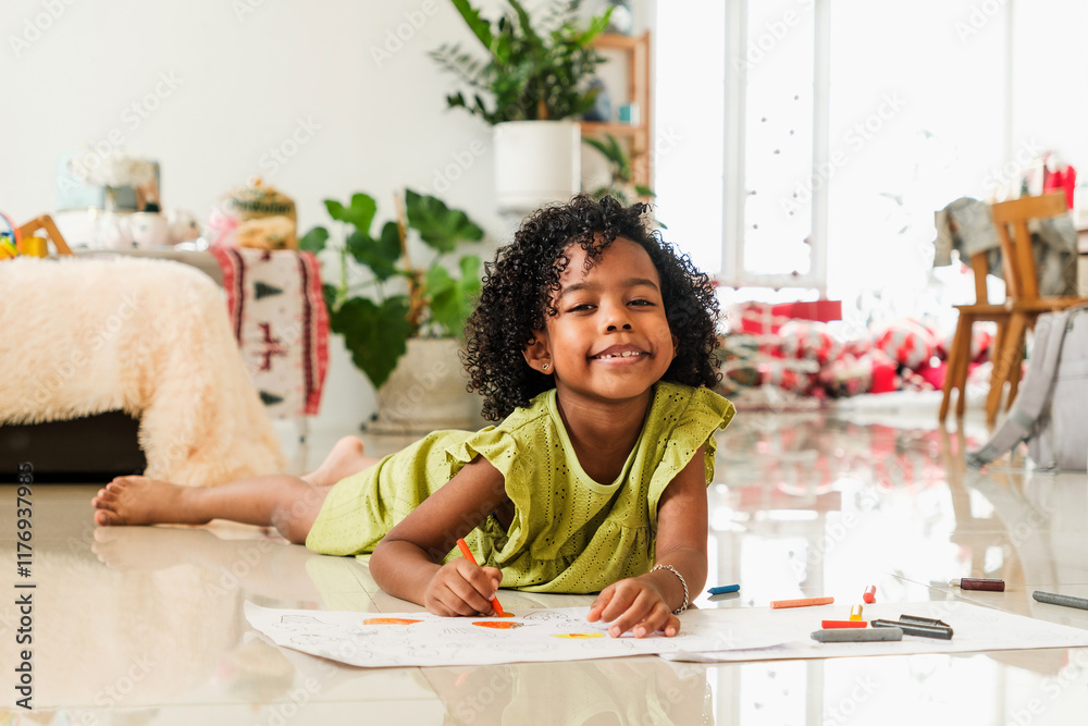 A cheerful girl lies on the floor, drawing with crayons in a cozy, brightly lit room filled with plants and holiday decorations. Happy diversity family concept. A cheerful girl lies on the floor, drawing with crayons in a cozy, brightly lit room filled with plants and holiday decorations. Happy diversity family concept.