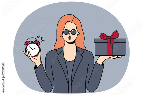 Shocked woman with gift and alarm clock in hands opens mouth in surprise after learning about being late for party. Businesswoman in formal black clothes and sunglasses holding gift for boyfriend