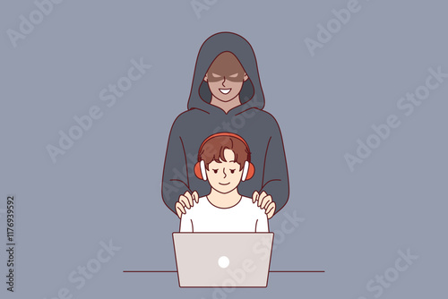 Cybercriminal stands behind little boy using laptop, for concept danger of pedophilia on internet. Cybercriminal creates risk for children visiting social networks and communicating on online forums