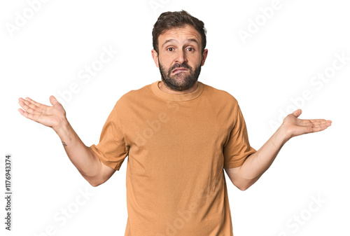 Photography Studio portrait of young Hispanic male confused and doubtful shrugging shoulders to hold a copy space